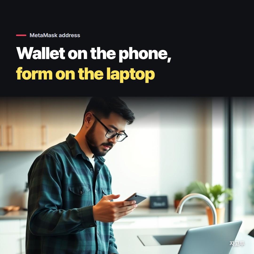 A man at a kitchen counter holding his phone next to an open laptop